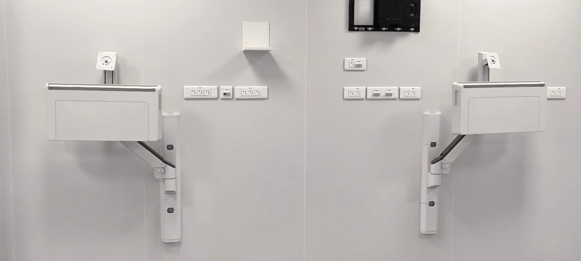 Deux stations murales Ergotron côte à côte dans une salle de soin, avant mise en service
