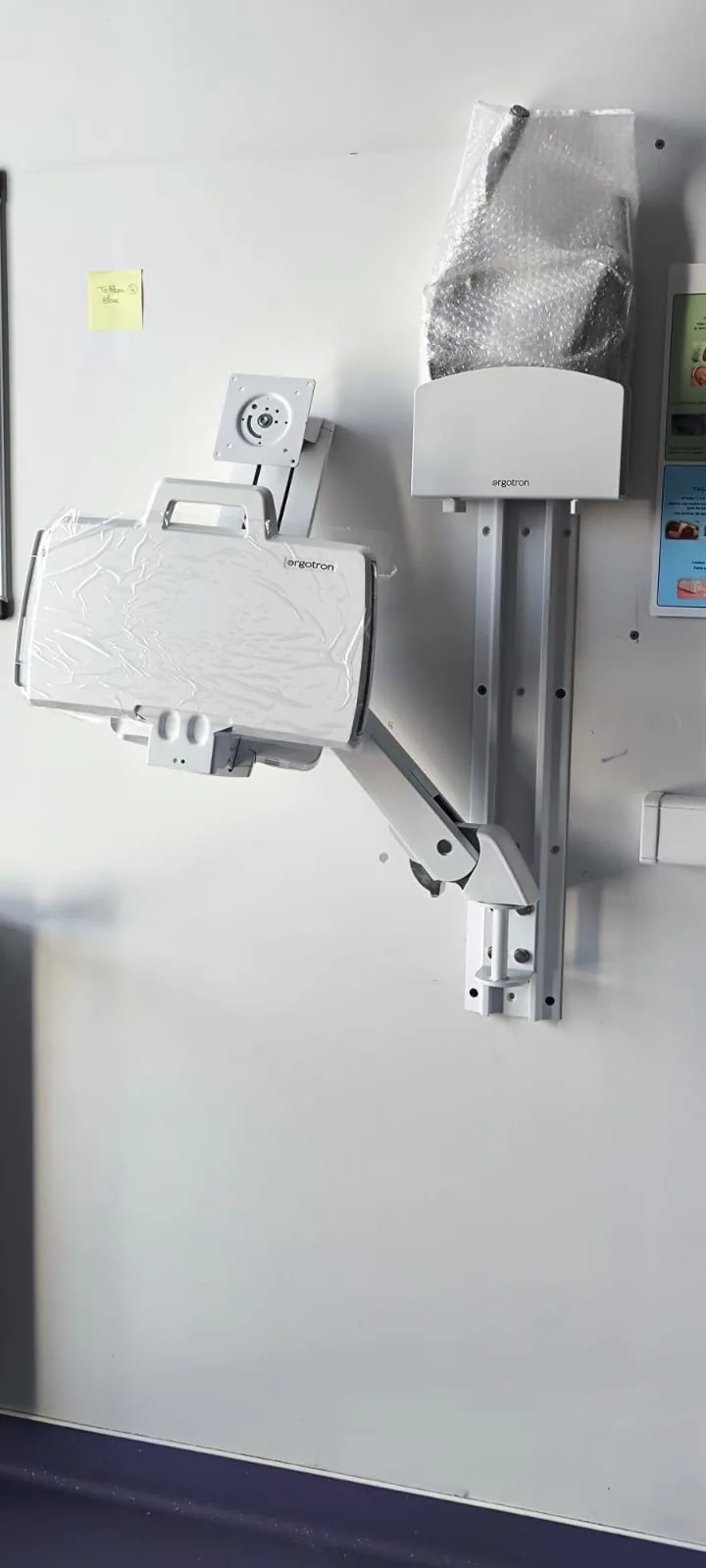 Bras et plateau Ergotron posés au mur, repère manuscrit de l'installateur