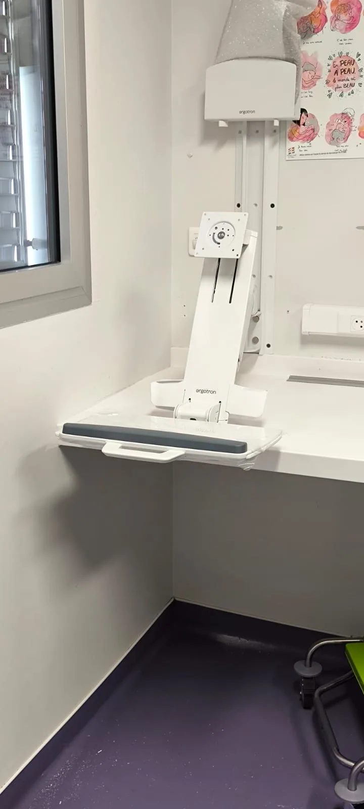 Station murale Ergotron déployée dans une chambre pédiatrique, plateau clavier ouvert